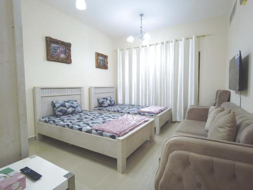 a living room with two beds and a couch at One Bedroom Twin Bed Fully Furnished in Sharjah