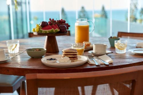 a wooden table with breakfast foods and orange juice at Jacob Resort Hadera in H̱adera
