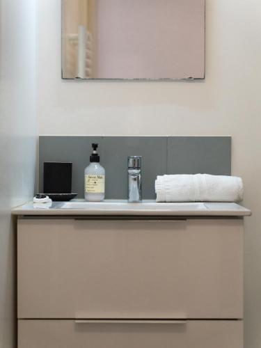 - un comptoir de salle de bains avec une bouteille de savon et un miroir dans l'établissement Le Refuge Urbain - Port à 2 pas & animaux acceptés, à Toulon