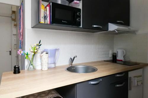 un comptoir de cuisine avec un évier et un micro-ondes dans l'établissement Escapade à 2 aux sables - rdc - cœur de ville, à Les Sables-dʼOlonne