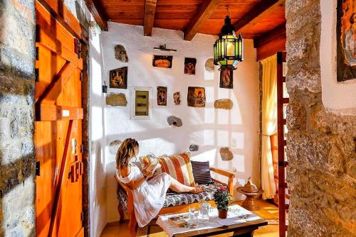 a woman sitting on a couch in a living room at Elounda Traditional Homes of Crete in Elounda