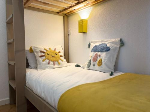 a small bedroom with a bed with two pillows at Brise Marine, piscine, confort entre dune et océan in Biscarrosse