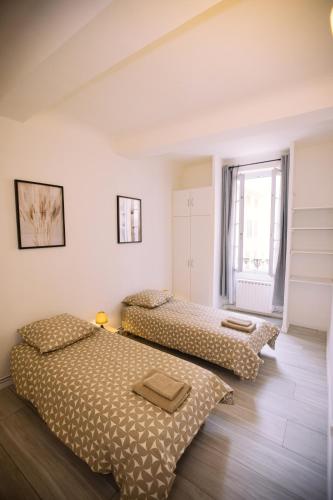 deux lits dans une chambre aux murs blancs dans l'établissement Grand appartement 3 chambres - Centre Toulon, à Toulon