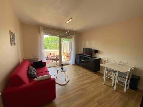 un salon avec un canapé rouge et une table dans l'établissement Studio Chill & Sun, à Aytré