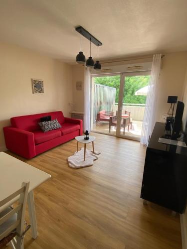 un salon avec un canapé rouge et une table dans l'établissement Studio Chill & Sun, à Aytré