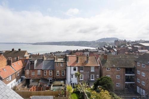 a view of a city with houses and the water at Just Beachy - 2 Bedroom Traditional cosy fisherman's cottage in Scarborough