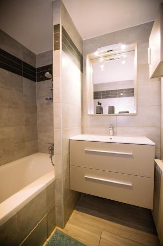 une salle de bain avec un lavabo, une baignoire et un miroir dans l'établissement Grand appartement 3 chambres - Centre Toulon, à Toulon