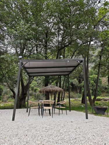 a shelter with a table and chairs in a park at River Glamping Kalopanayiotis in Kalopanayiotis