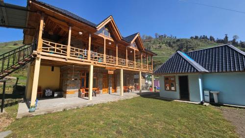 a large wooden house with a mountain in the background at Freebird Nest Retreat in Jibhi