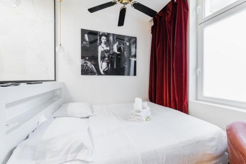 une chambre avec un lit blanc et un rideau rouge dans l'établissement Studio lumineux et moderne proche du metro - 2P, à Paris