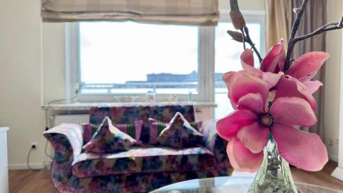 a vase with pink flowers on a table in a living room at 6-401, Extravagante Strandwohnung, Art Nouveau meets französischen Landhausstil! 1Zimmer in Westerland (Sylt)