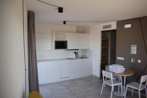 une cuisine avec des armoires blanches et une table et des chaises dans l'établissement Garoupe T3 Bloom Le Spot, à La Ciotat