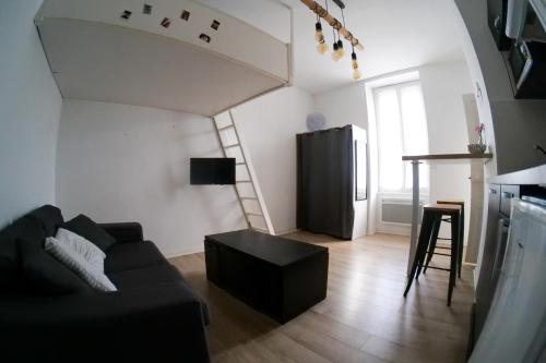 - un salon avec un canapé noir et un escalier dans l'établissement Studio douillet entre ville et océan - Etage 1 - Proche toutes commodités, à Les Sables-dʼOlonne