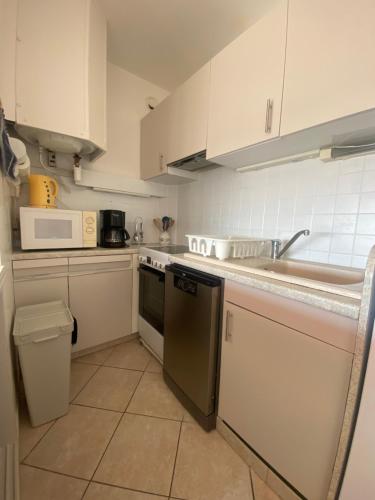 - une petite cuisine avec des placards blancs et un lave-vaisselle dans l'établissement PORT CAMARGUE – BEL APPARTEMENT CLIMATISÉ AVEC VUE MER, TERRASSE PARKING – 4 PERSONNES, au Grau-du-Roi