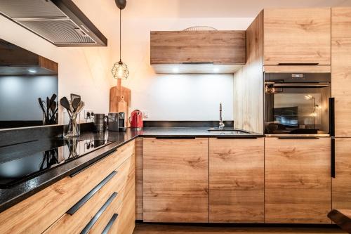 une cuisine avec des placards en bois et des comptoirs noirs dans l'établissement Apartment Osmose 002, Châtel - by EMERALD STAY, à Châtel