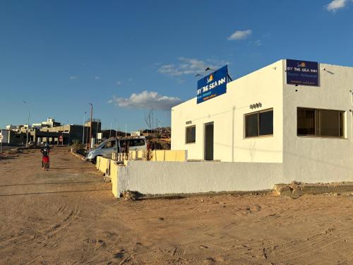 a white building with a sign on the side of it at Camel Dive Club By The Sea Inn in Jurf ad Darāwīsh