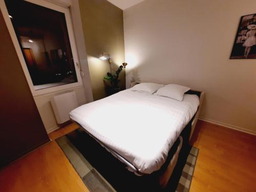 une chambre avec un lit avec des draps blancs et une fenêtre dans l'établissement Le Garibaldi, à Dijon