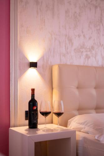 two glasses of wine on a table next to a bed at Hotel Delta in Durrës