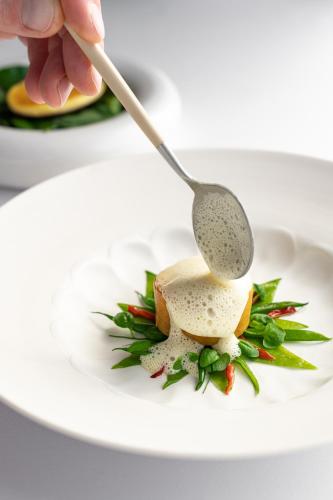 a person eating food with a spoon on a plate at La Chèvre d'Or in Èze