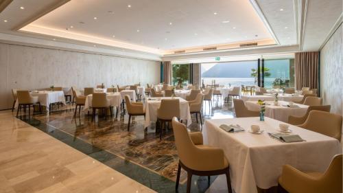 a restaurant with white tables and chairs and windows at Swiss Diamond Boutique Hotel - La Romantica in Melide