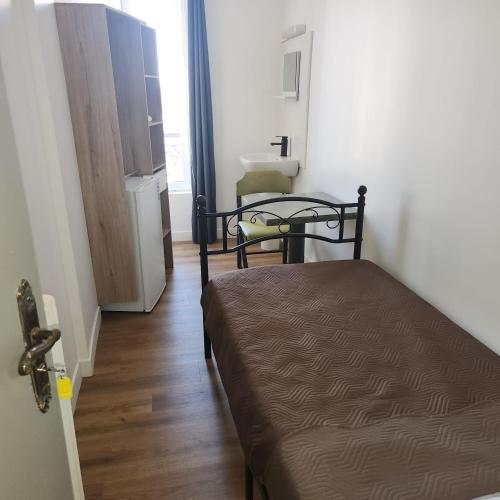 a bedroom with a bed and a table in a room at Hôtel de l'Europe in Pantin