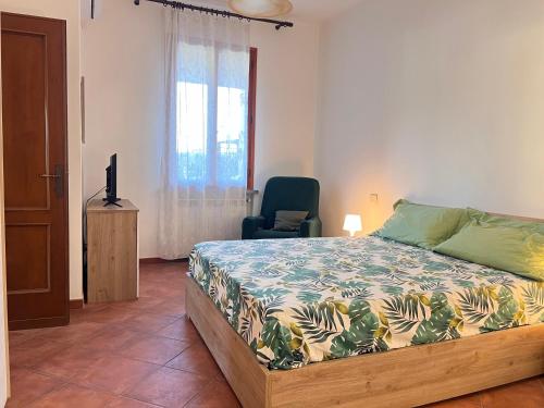 a bedroom with a bed and a chair and a window at Villa Biba tra Lucca e Pisa in Avane