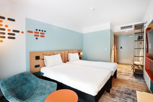 a bedroom with a large bed and a chair at ibis Styles Kraków Centrum in Kraków