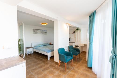een slaapkamer met een bed en twee blauwe stoelen bij Apartman Tekoma Herceg Novi in Herceg-Novi