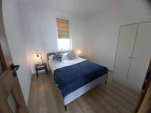 a bedroom with a bed with a blue blanket and a window at Apartamenty Marta i Michał Dziwnówek in Dziwnówek