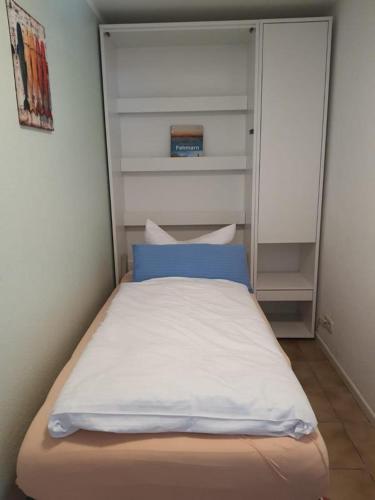 a small bed with a blue pillow in a room at Haus Achtern Diek in erster Reihe am Meer in Fehmarn