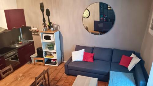 a living room with a blue couch and a mirror at Appartement pour 4 personnes dans une rue très calme in Saint-Laurent-le-Minier