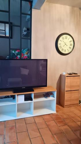 a clock on the wall next to a television at Appartement pour 4 personnes dans une rue très calme in Saint-Laurent-le-Minier