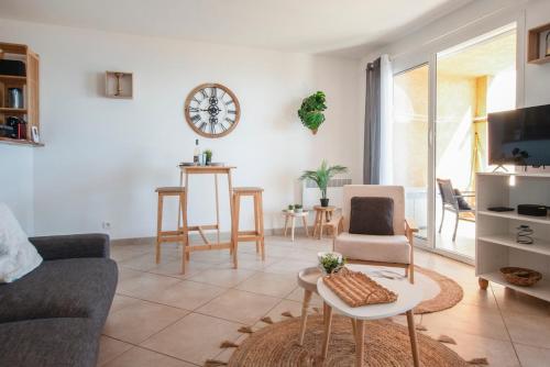 un salon avec un canapé et une horloge au mur dans l'établissement Appartement Vue Mer Proche Plage, à Luri