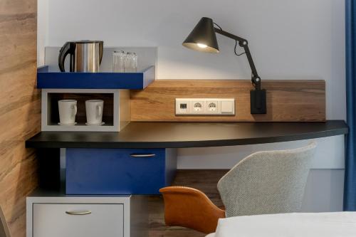 a desk with a lamp and a chair at Mercure Hotel Hamburg Mitte in Hamburg
