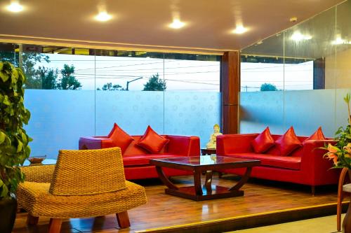 a living room with red couches and a table and chairs at White Ridge Hotel in Dharamshala
