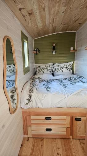 - un lit dans une petite maison avec un miroir dans l'établissement Roulotte domaine Farigoule, à Baron