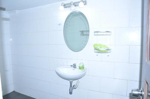 a white bathroom with a sink and a mirror at Velkommen Guesthouse Phnom Penh in Phnom Penh