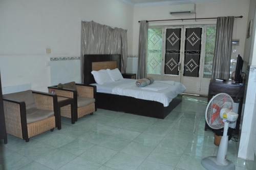 a bedroom with a bed and a chair and a fan at Velkommen Guesthouse Phnom Penh in Phnom Penh