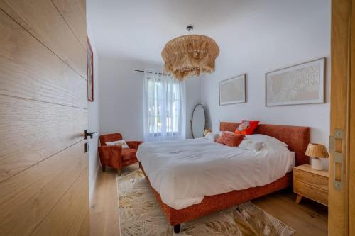 - une chambre avec un lit, une chaise et un lustre dans l'établissement La Villa des Vagues, à Châtelaillon-Plage