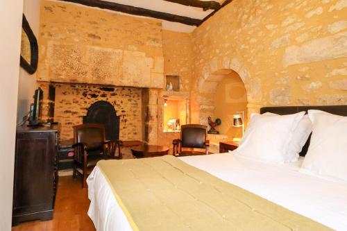 - une chambre avec un grand lit et une cheminée dans l'établissement Le Coq de Landry, à Sarlat-la-Canéda