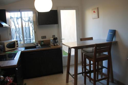 une cuisine avec une table, deux chaises et un comptoir dans l'établissement logement entier dans maison pour 4, à Villeneuve-lès-Avignon