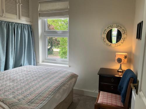 a bedroom with a bed and a mirror and a window at Terraced Garden House Three Bedrooms in Stamford
