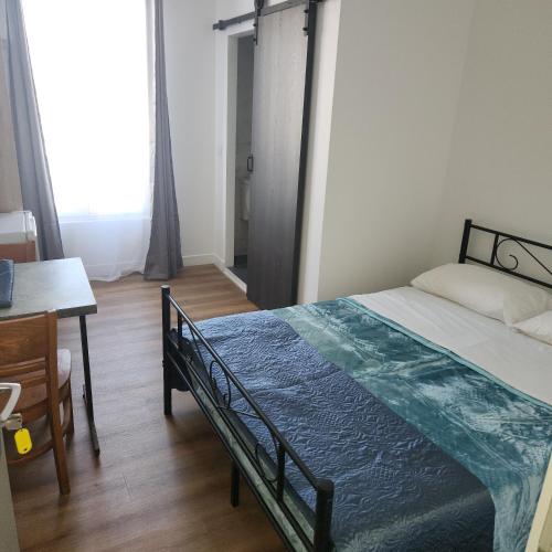 a bedroom with a bed and a desk and a window at Hôtel de l'Europe in Pantin