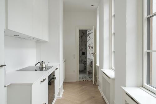 a white kitchen with a sink and a hallway at Latin Quarter by Daniel&Jacob's in Copenhagen