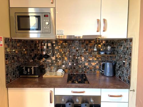 a kitchen with a stove and a microwave at Melbury Rooms & Studios in Exeter