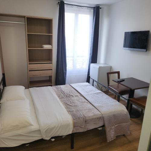 a bedroom with a bed and a window and a table at Hôtel de l'Europe in Pantin
