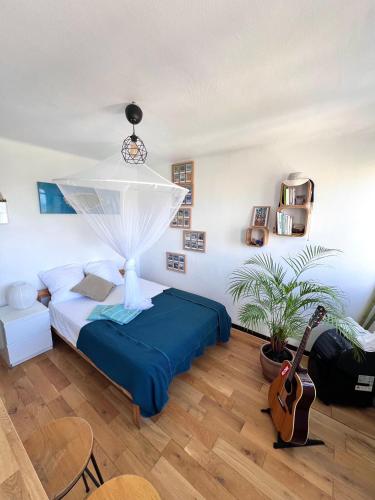 - une chambre avec un lit et une guitare dans l'établissement Cosy studio en étage résidence front de mer, à Palavas-les-Flots