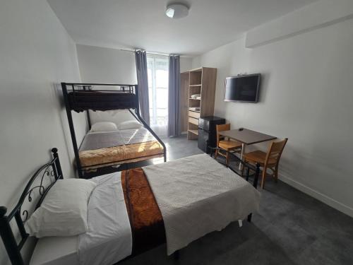 a bedroom with two beds and a table and a desk at Hôtel de l'Europe in Pantin