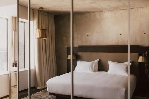a bedroom with a large white bed with glass walls at Maison Heler Metz, Curio Collection By Hilton in Metz
