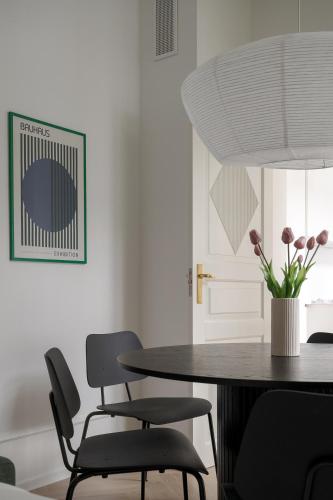 a dining room table with chairs and a vase with flowers at Latin Quarter by Daniel&Jacob's in Copenhagen
